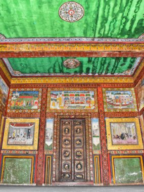 Gujarat, Vadodara 'da tarihi bir bina olan 150 yıllık Tambekar Wada' nın içindeki canlı duvarlar üzerindeki karmaşık mitolojik ve Hindu kültürel tablolarıyla çevrili ahşap kapılar..