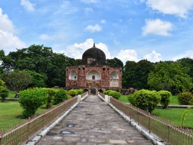 Kutub-Ud-Din Muhammad Khan 'ın Vadodara, Gujarat' taki 450 yıllık mozolesinde karmaşık mimari, yemyeşil çevre ve berrak mavi gökyüzü altında canlı peyzaj yer alıyor..