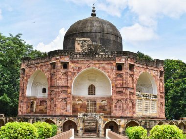 Vadodara, Gujarat 'taki 450 yaşındaki Kutub-Ud-Din Muhammad Khan' ın antik mozolesinde karmaşık taş mimarisi, simetrik kemerler ve parlak bir gökyüzünün altında yemyeşil bir kubbe ile çevrili tarihi bir kubbe sergileniyor..