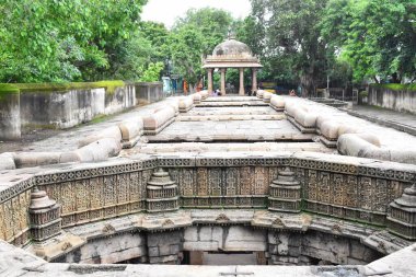 Ahmedabad 'da Bai Harir Stepwell' in tarihi eserlerinde, verimli yeşilliklerle çevrili karmaşık taş oymaları, Gujarat 'ın antik mimarisinin kültürel mirasını vurguluyor..