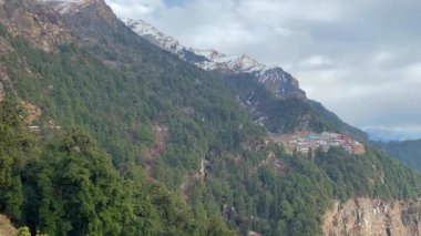 A wide, clear view of the Chopta access road and expansive valley below, captured mid-way up the mountain from the Corner Stone viewpoint in Uttarakhand at 8,500 feet altitude in the Himalayas.