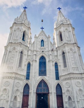 Velankanni 'deki ikonik beyaz bazilika karmaşık Gotik mimari, yüksek kuleler ve mavi gökyüzünün altında boyalı camlar içerir..