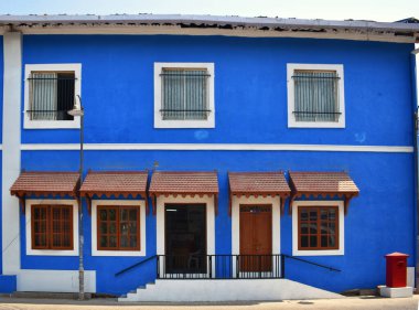 A vibrant 30-year-old heritage blue colored colonial-style building with wooden windows and doors in Daman's inner city.