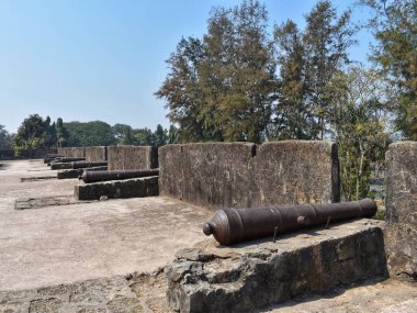 Eski toplar, Gujarat 'taki Moti Daman Kalesi' nde 300 yıllık engebeli taş duvarların üzerinde duruyor. Kale, temiz mavi gökyüzü altında Hindistan 'ın mimari ve tarihi mirasına bir bakış sunuyor..