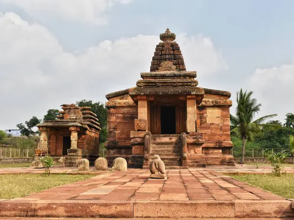 Aihole, Karnataka 'daki tarihi Hucchamalli Tapınağı, yeşillik ve bulutlu bir günde açık gökyüzü ile çevrili antik kumtaşı mimarisini sergiliyor..