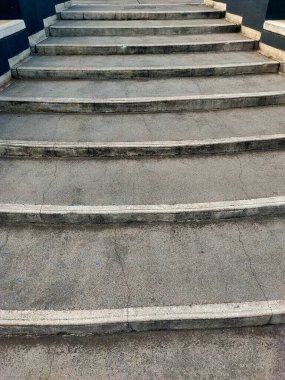 Geniş, yıpranmış beton merdivenlerin alçak açılı görüntüsü, yukarı doğru, ilerlemeyi ve mimari basitliği sembolize ediyor
