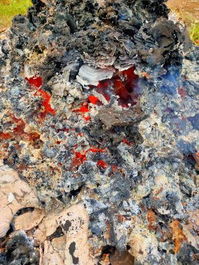 Kara kül ve yanmış molozların arasında yanan, yanan kırmızı közlerin büyüleyici yakın çekimi yoğun sıcaklığı ve yangının neticesini iletir..