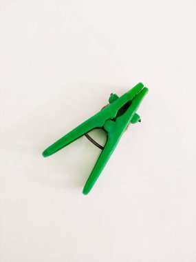 Saf beyaz bir yüzey üzerinde neşeli yeşil bir mandal duruyor. Sürdürülebilir yaşam, hava kurutma ve çevresel bilinci temsil eder. Çevre dostu ve yaşam tarzı içeriği için ideal.