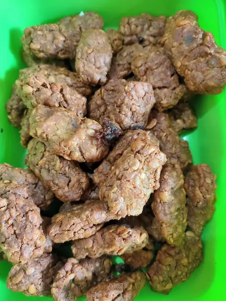 Mayalanmış soya fasulyesinden yapılmış geleneksel Endonezya atıştırmalığı. Parlak yeşil bir konteynırda servis ediliyor, vegan ve yerel yemek temaları için mükemmel..
