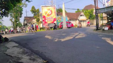 Doğu Java 'nın Malang kentindeki yoğun bir kavşakta ustalıkla motosiklet ve araçları yöneten gayri resmi trafik düzenleyicisi 