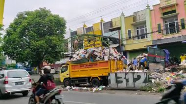 Bir belediye çöp kamyonu, Malang, Endonezya 'daki kentsel sağlık sorunları ve çevresel etkileri vurgulayan muazzam bir atık yığınıyla mücadele ediyor. Doğu Java. 24 Haziran 2025