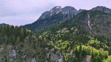 Almanya, Bavyera 'daki Neuschwanstein Kalesi' nin insansız hava aracı tarafından ele geçirilmiş çarpıcı görüntüleri. Dağlar, ormanlar ve dramatik manzaralarla çevrili ikonik masal şatosu. 19. yüzyıl Romanesk Diriliş mimarisinin mükemmel bir örneği..