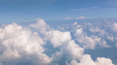 Dramatik beyaz bulutlar ve mavi gökyüzü uçak penceresinden görülebilir.