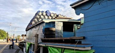 Geleneksel ahşap bir tekne, beton set boyunca demirlemiş plastik varillerden oluşan yüksek bir piramit ile bir mavnaya dönüştürüldü.