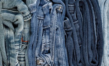 Farklı kot pantolonlar renklerine göre düzgünce katlanır ve düzenlenir.