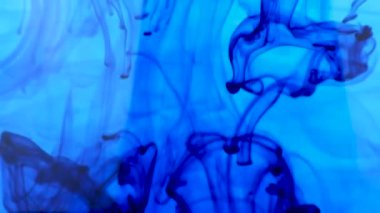 Mavi mürekkep zarif bir şekilde berrak suda kıvrılarak karmaşık tasarımlar oluşturur.