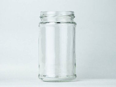 Şeffaf cam bir kavanoz tarafsız bir arkaplanda boş duruyor.