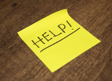 Tahta bir yüzeye yerleştirilmiş parlak sarı yapışkan bir not.