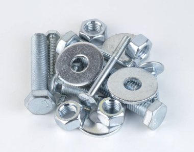 Metal vidalar ve fındıklar beyaz arka planda izole edilmiş. Endüstriyel çelik donanım cıvataları ve fındıkları