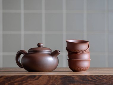 Kahverengi geleneksel seramik çaydanlık masanın üzerinde istiflenmiş fincanların yanında duruyor. Yüksek kalite fotoğraf