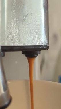 Koyu espresso makineden yavaşça beyaz bir kaba dökülür. Yüksek kalite 4k görüntü