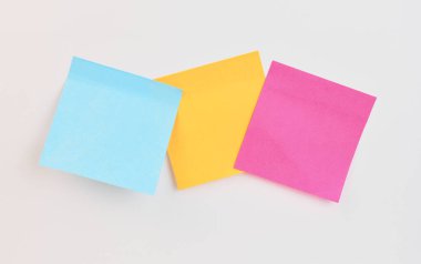 Mavi, sarı ve pembe renkli üç yapışkan nota yaratıcı bir şekilde görüntülenir.
