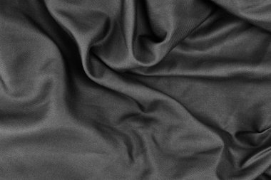 Yumuşak, koyu bir kumaş nazikçe katlanarak zengin bir doku oluşturur.