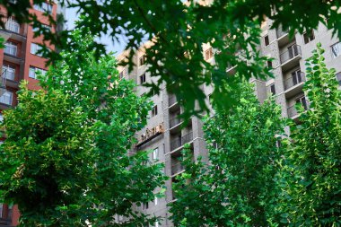 Gündüz vakti kentsel çevrede yeşilliği olan modern apartman binası