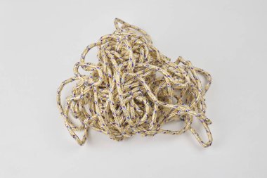 Karmaşık bir ip yığını düz beyaz bir yüzeyde yatıyor.