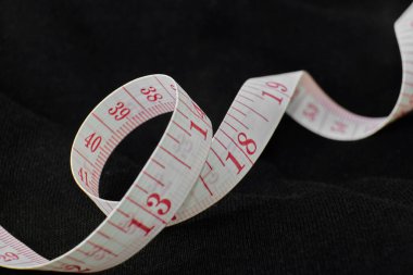 Karanlık bir yüzeyde duran esnek ölçüm bandı.