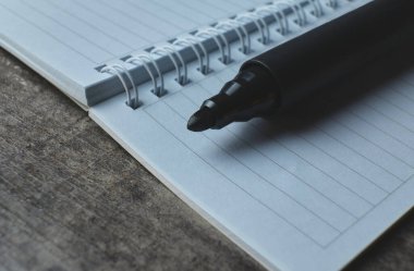 Çizgili bir not defterine siyah bir işaret konur.