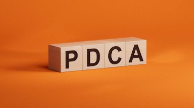 PDCA iş sözcüğüne sahip ahşap küpler. Ahşap küplere yakın çekim, turuncu arka planda 3D iş konsepti..