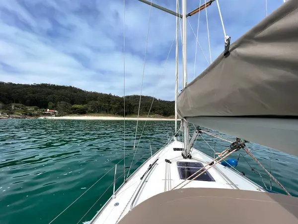 Bir yelkenlinin güvertesinden yalnız bir kumsala ulaşan manzara.