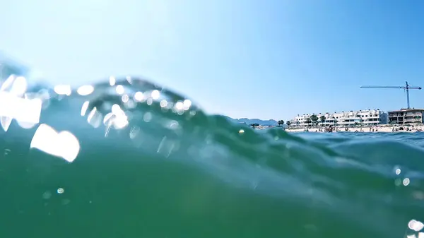 Akdeniz 'de mavi su ve sahil beldeleri olan bir deniz dalgasının yakın plan çekimi.