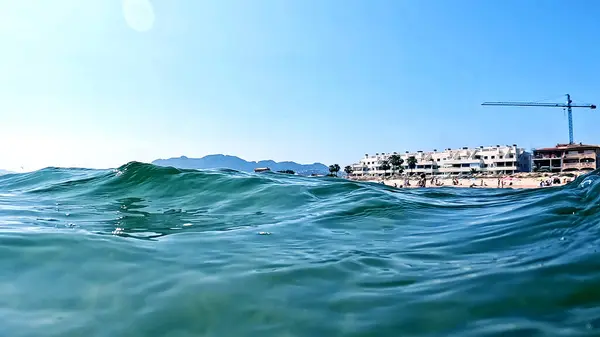 Akdeniz 'de mavi su ve sahil beldeleri olan bir deniz dalgasının yakın plan çekimi.