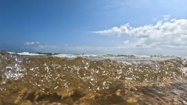Sahile ulaşan dalgalar kameraya sıçrıyor.