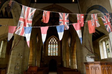 Güney Harting, Batı Sussex, İngiltere. 6 Mayıs 2025. 80. Zafer Günü kutlamaları sırasında kilisenin içinde bayraklar sallanıyor..