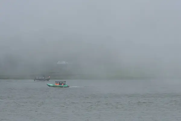 Bulanık kıyı şeridiyle Şafak vakti Sisli Göldeki Tekneler