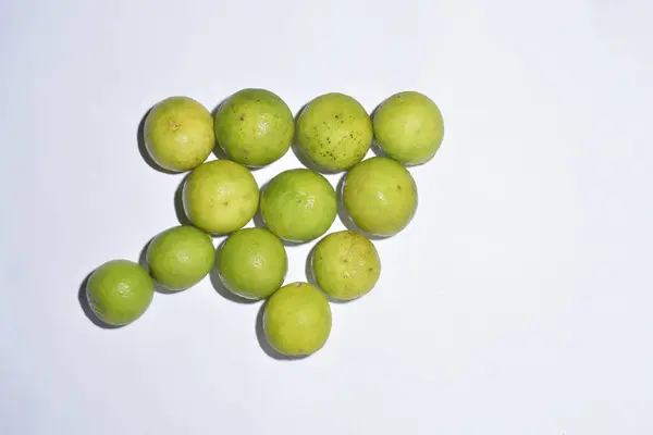 Taze, canlı yeşil limon kümesi, bazıları hafif sararmış, temiz beyaz arka planda düzenlenmiş. Bu parlak ve lezzetli görüntü sağlıklı beslenme, yemek malzemeleri, taze üretim, turunçgiller ve ilgili konular için mükemmeldir. 