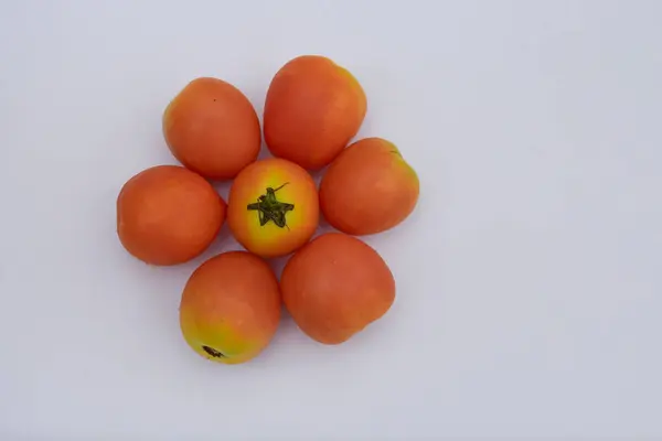 Taze, olgun domates kümesi, turuncu ve sarı renklerin güzel bir karışımını sergiliyor, temiz beyaz bir yüzey üzerinde çiçeğe benzer bir desende ustalıkla sıralanmış. Bu canlı ve sağlıklı ürünler mutfak temaları, sağlıklı beslenme ve bahçe işleri için mükemmeldir.