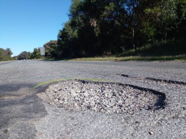 Port Elizabeth, Güney Afrika - 7 Ağustos 2025: Victoria Drive 'daki bu çukur bu yolda seyahat etmenin ne kadar tehlikeli olduğunun bir örneğidir. Sokak lambaları da yok.. 