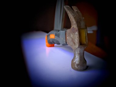 Siyah arka planda çekiç tutan bir elin yakın plan çekimi.