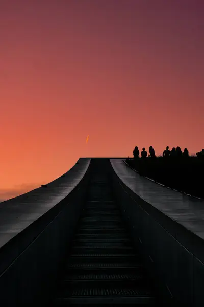 Tepesinde bir grup insan olan bir binanın üzerinde güzel bir günbatımı.