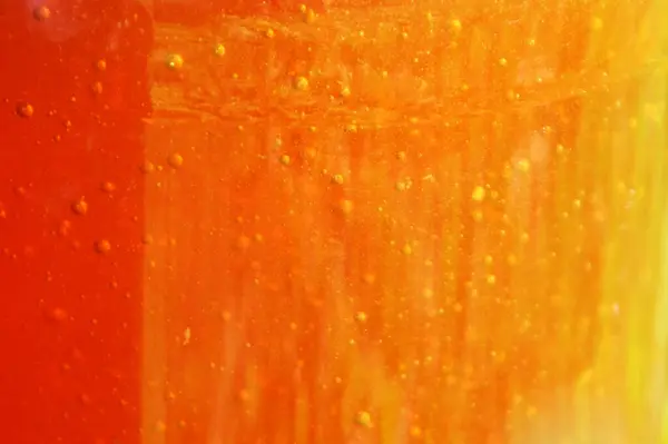 Kavanozda hava kabarcıkları olan ve arka plan renk değişiminin arkasında güneş ışığı olan bal.