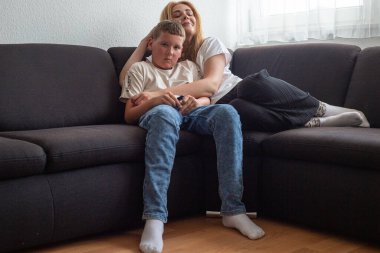 Anne ve oğlu kanepede oturan