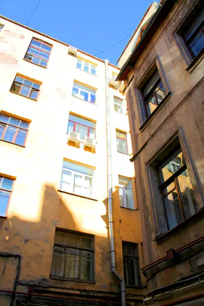 Şehirdeki eski ev cephesi, yüksek binaları olan avlu.