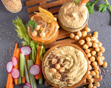 Nohut, keten tohumu ve taze sebzelerle karışık humus kaseleri. Atıştırmalıklar ve Akdeniz mutfağı için sağlıklı ev yapımı sos ideal.