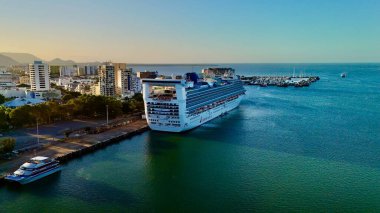 Cairns, Queensland, Avustralya 'nın hava fotoğrafları Cairns Cruise Liner Terminali, Cairns Kongre Merkezi ve çevresindeki rıhtım ve marinaya yanaşmış yolcu gemilerini gösteriyor. Görüntüler şehir siluetini vurguluyor, yağmur ormanlarıyla kaplı.