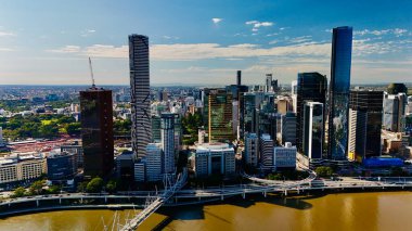Queensland, Avustralya 'daki Brisbane CBD' nin hava görüntüsü modern silueti, Brisbane Nehri ve çevre kentsel manzarayı gözler önüne seriyor. Yüksek binalar, köprüler ve nehir kenarındaki gelişmelerle fotoğraf, bir tanesinin dinamik enerjisini yakalıyor.