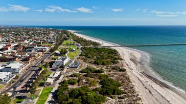 Semaphore Beach ve Jetty, Adelaide, Güney Avustralya: Bu 4K hava aracı görüntüsü, turkuaz okyanus suları üzerinde uzanan semforik Semaphore Jetty 'yi, el değmemiş kumlu plajı ve komşu kıyı banliyölerini gösteriyor. Güneşli bir havada yakalandılar.